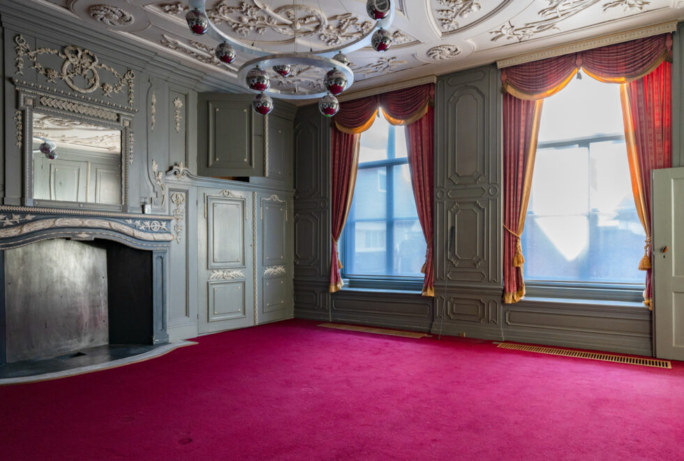 Lege museumzaal met groene betimmering en rood tapijt