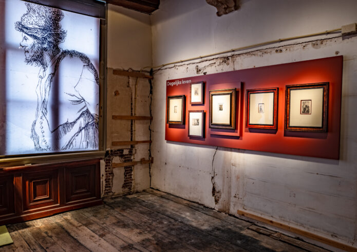Vergroot de foto: Rood paneel met etsen tegen ruwe wanden en lichtbak met geëtste manfiguur